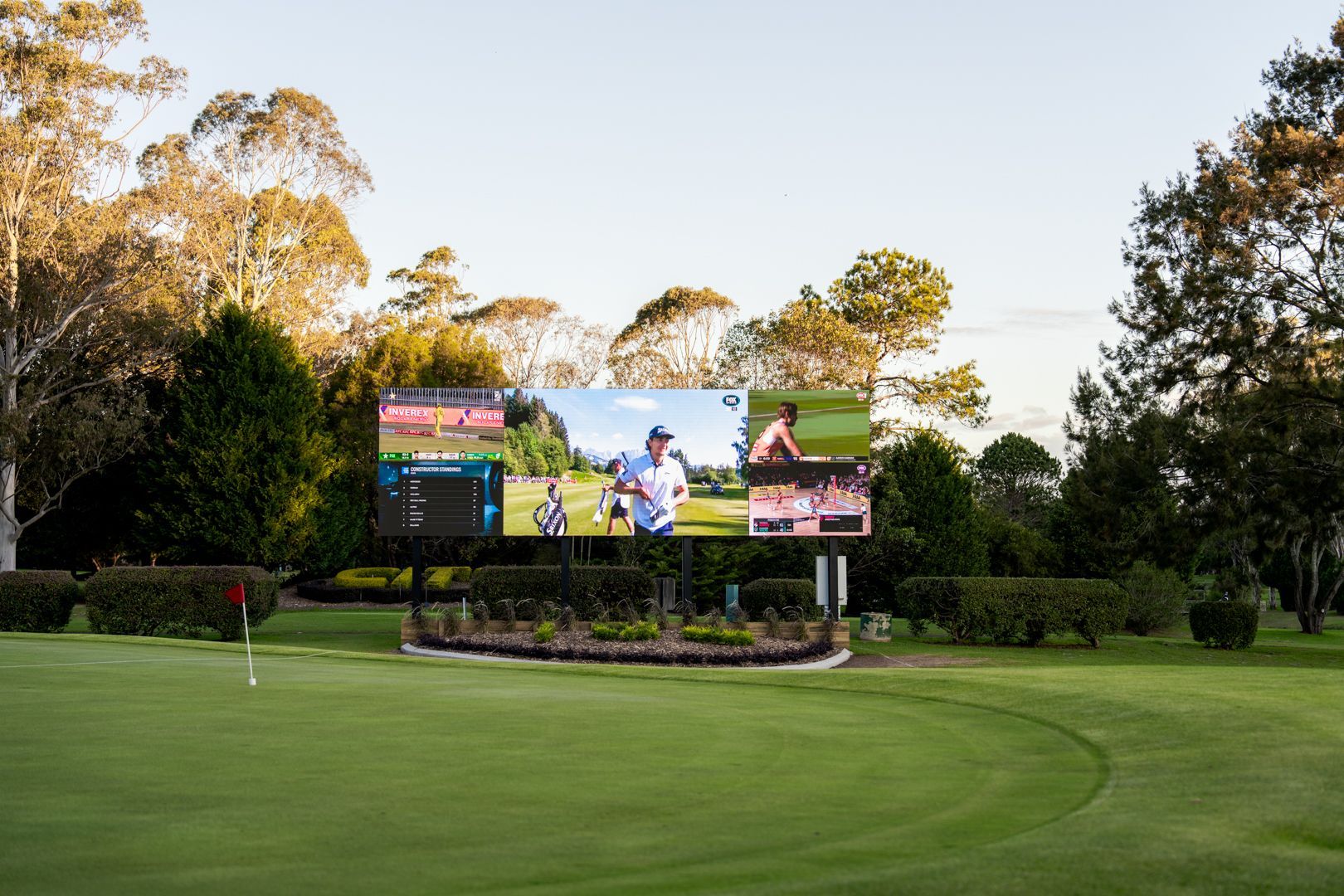 Golf course with large outdoor video screen near a green at sunset
