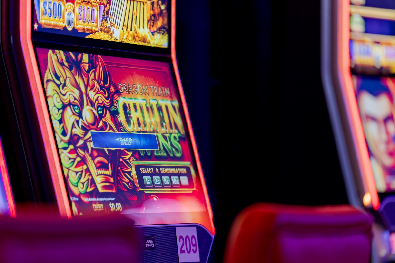 Row of colourful slot machines with neon lights in a dim casino interior