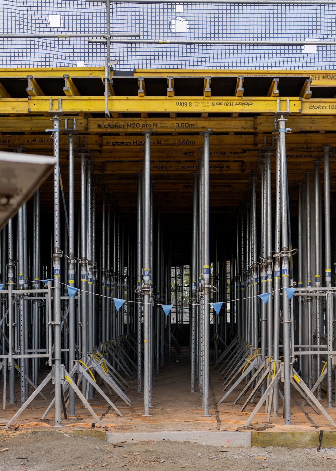 Scaffolding and steel support poles under a yellow construction platform at a building site