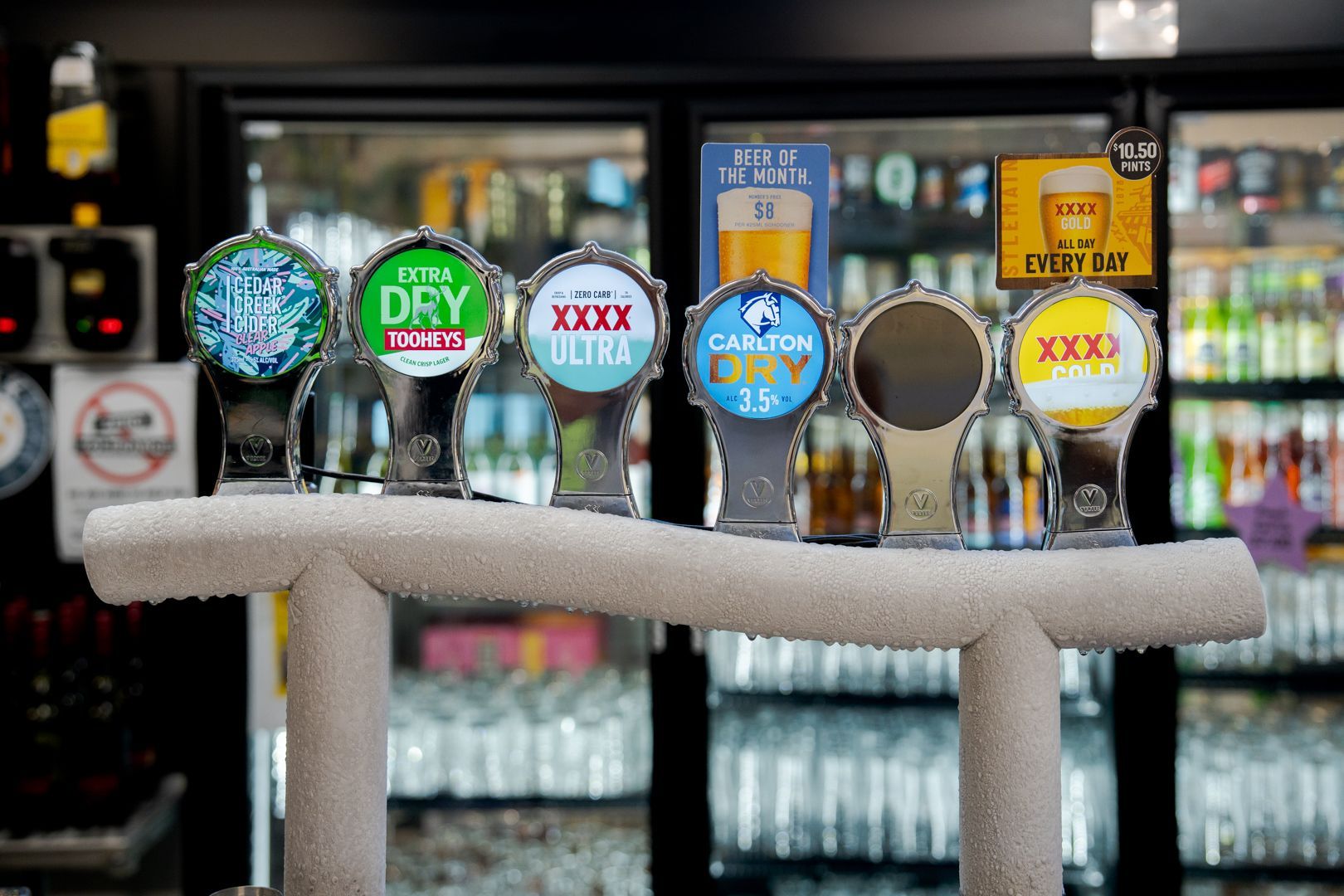 Row of colourful beer taps in a bar, including Dry and XXX Ultra labels