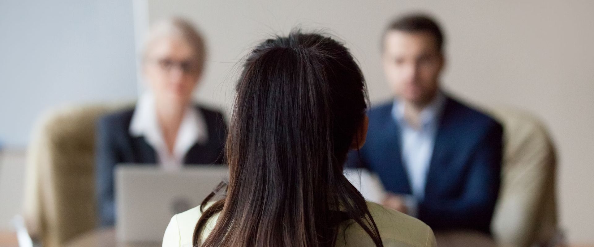 A woman is sitting at a table during a job interview.