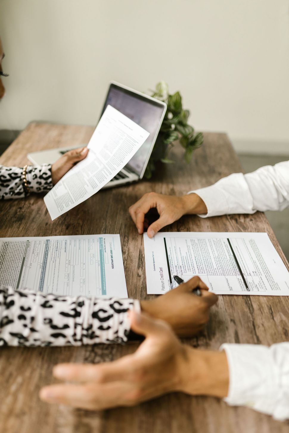 People reviewing documents and discussing paperwork at a wooden table indoors.