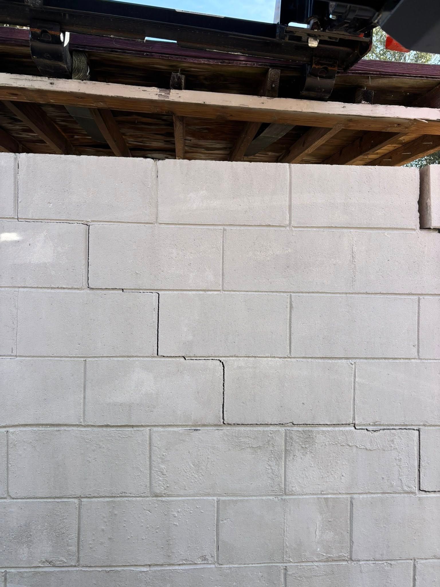 A newly constructed gray concrete block wall under a wooden ceiling structure.