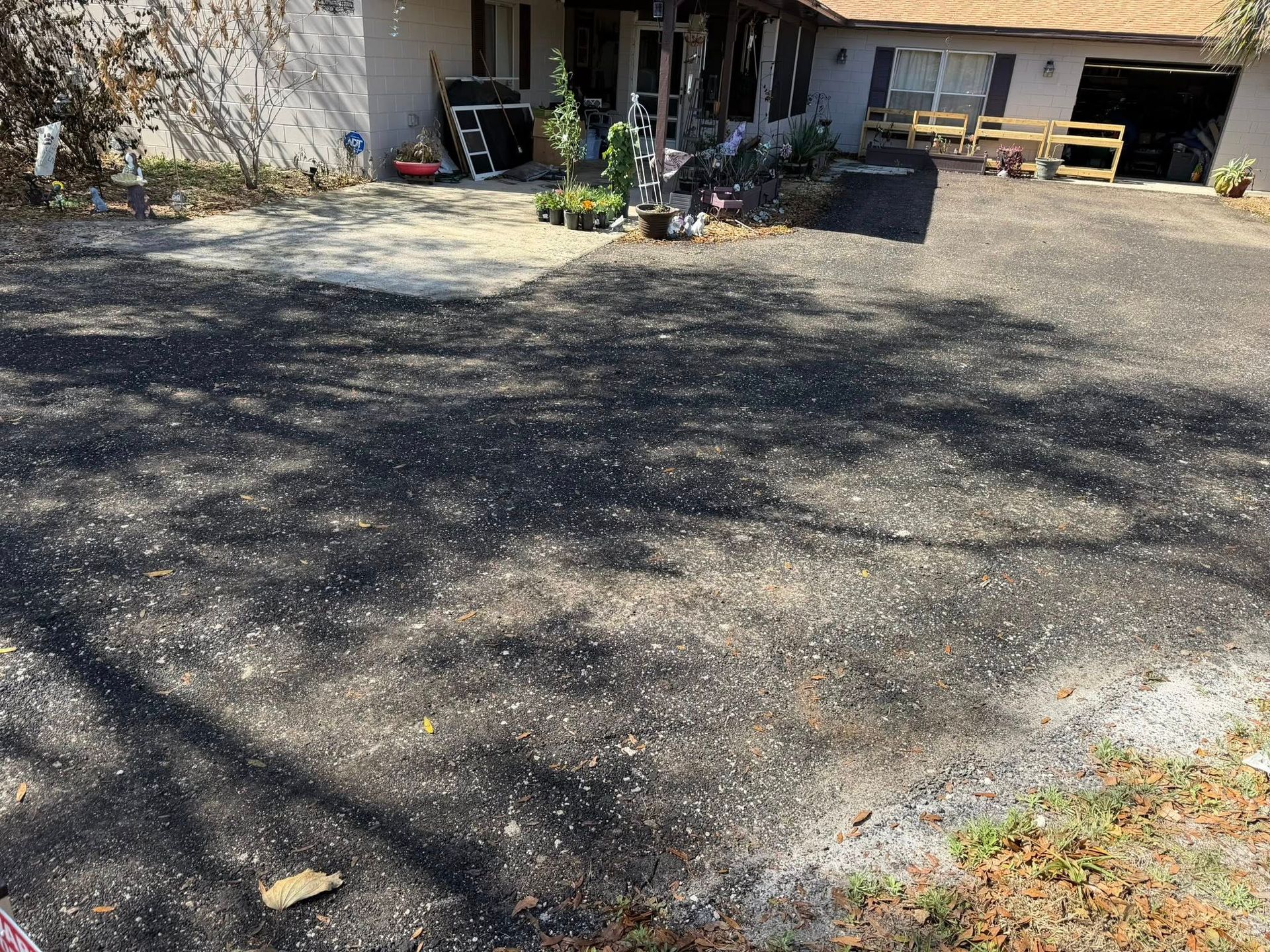A residential home with a large, dark gravel driveway leading to a garage and a concrete walkway.