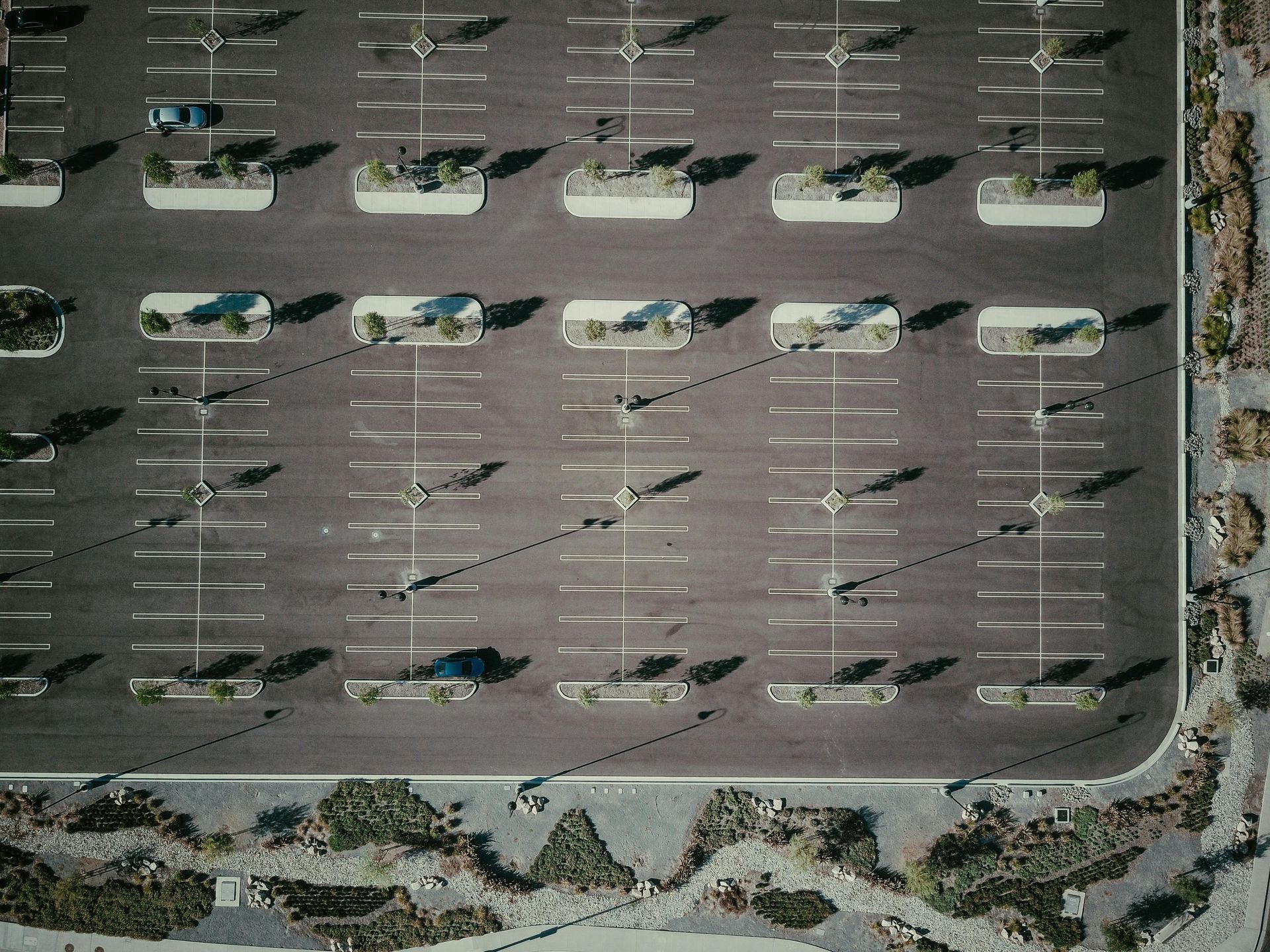 Nearly empty parking lot with scattered cars and long shadows