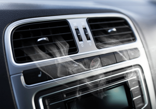 Car dashboard with air vents, silver trim, and visible vapor.