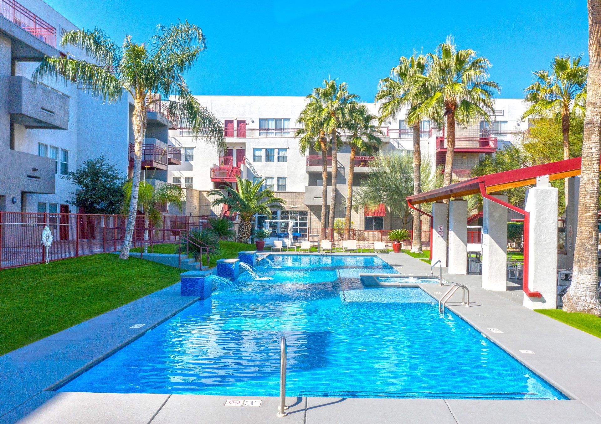 Host a BBQ using the grills at the pool! An image of the pool and hot tub with lounge chairs at the center of the complex.