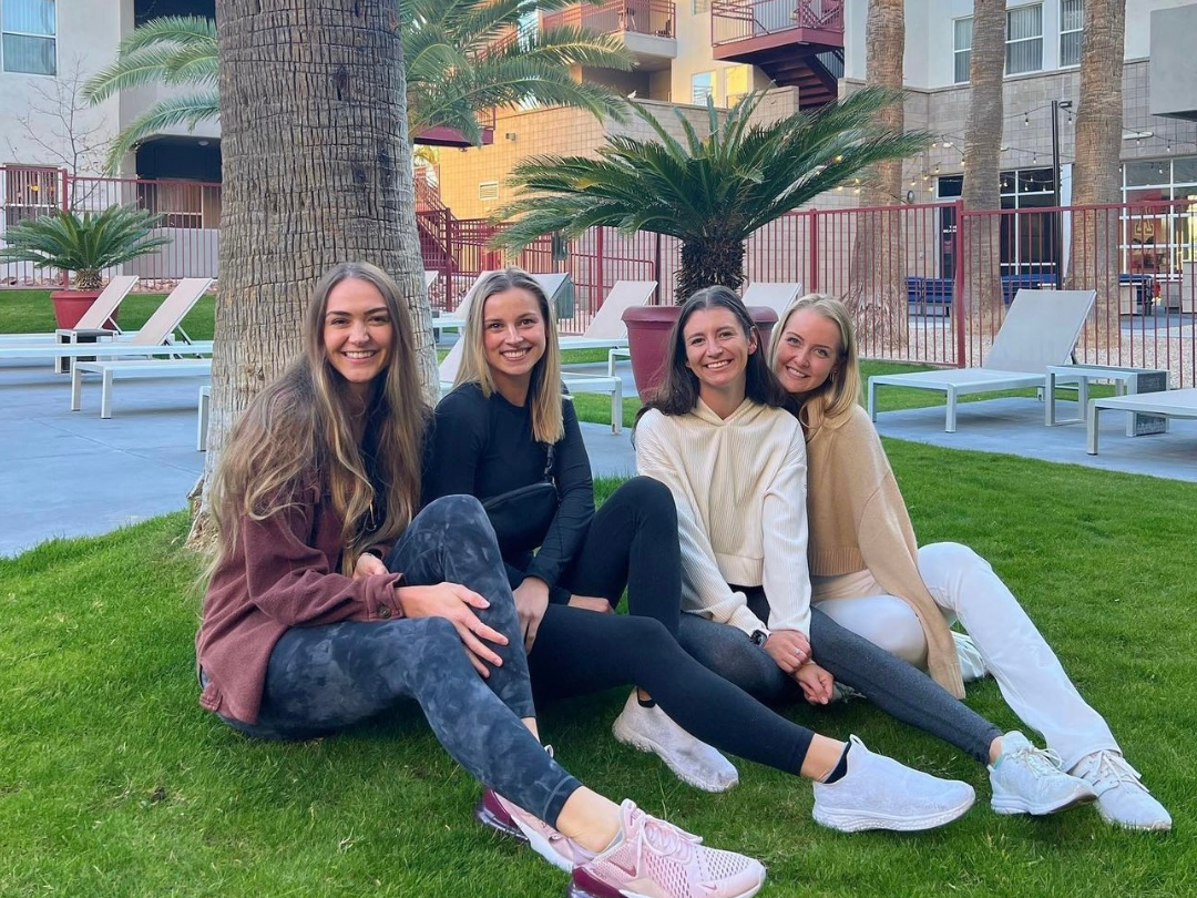 Plan Fall events with your roommates! A group of four female college student residents are smiling while sitting by the pool in their sweaters at The Seasons.