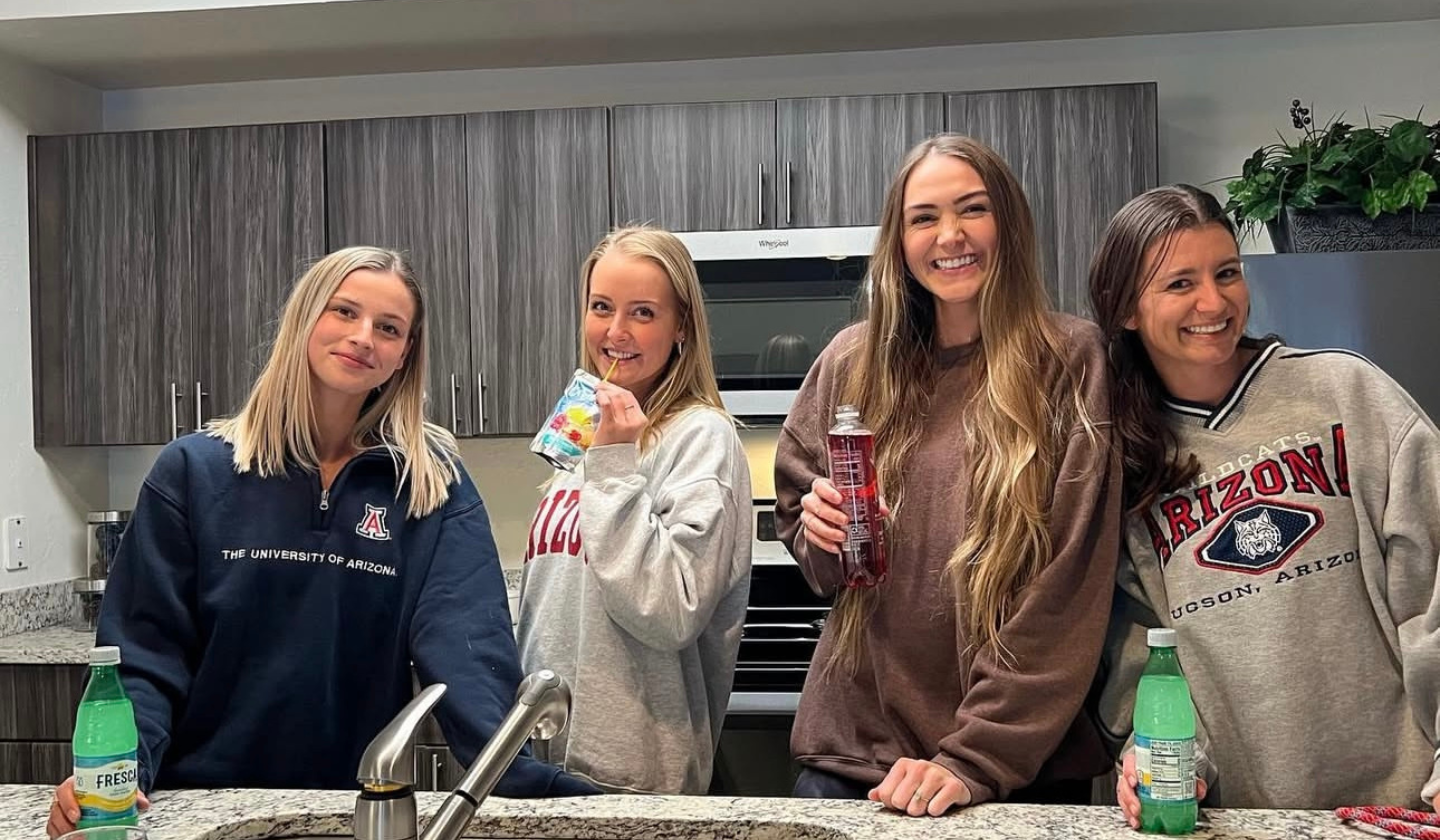 Four female residents enjoying juices and sodas while spending time together in their apartment's kitchen.
