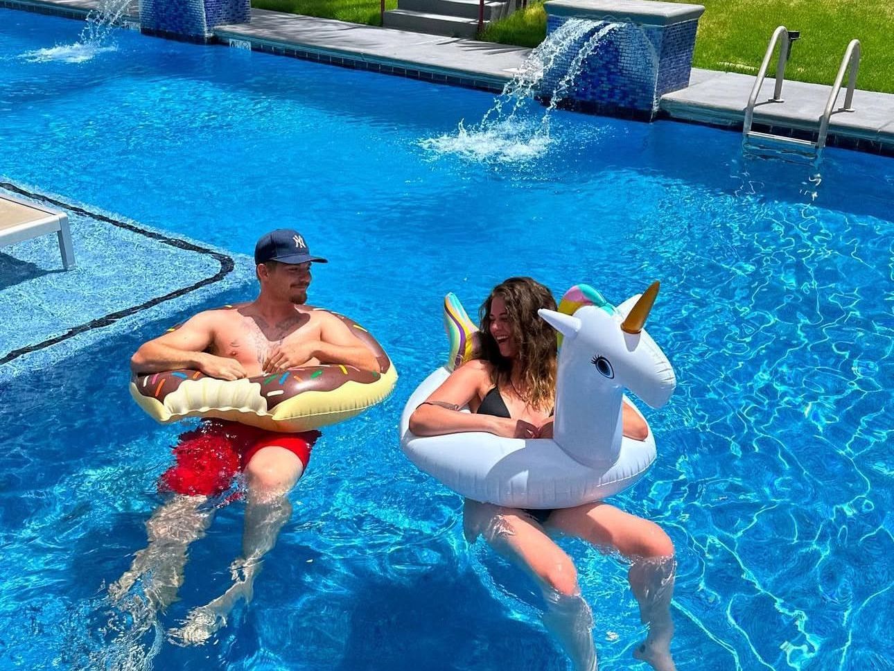 Enjoy our resort style pool and hot tub year round! A male and female resident floating in the resort style pool at The Seasons.