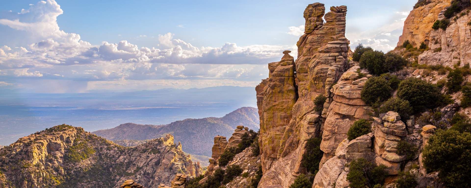Hike or bike the trails of Mount Lemmon! A skyview showcasing peaks and valleys of Mount Lemmon with a light blue sky and clouds.