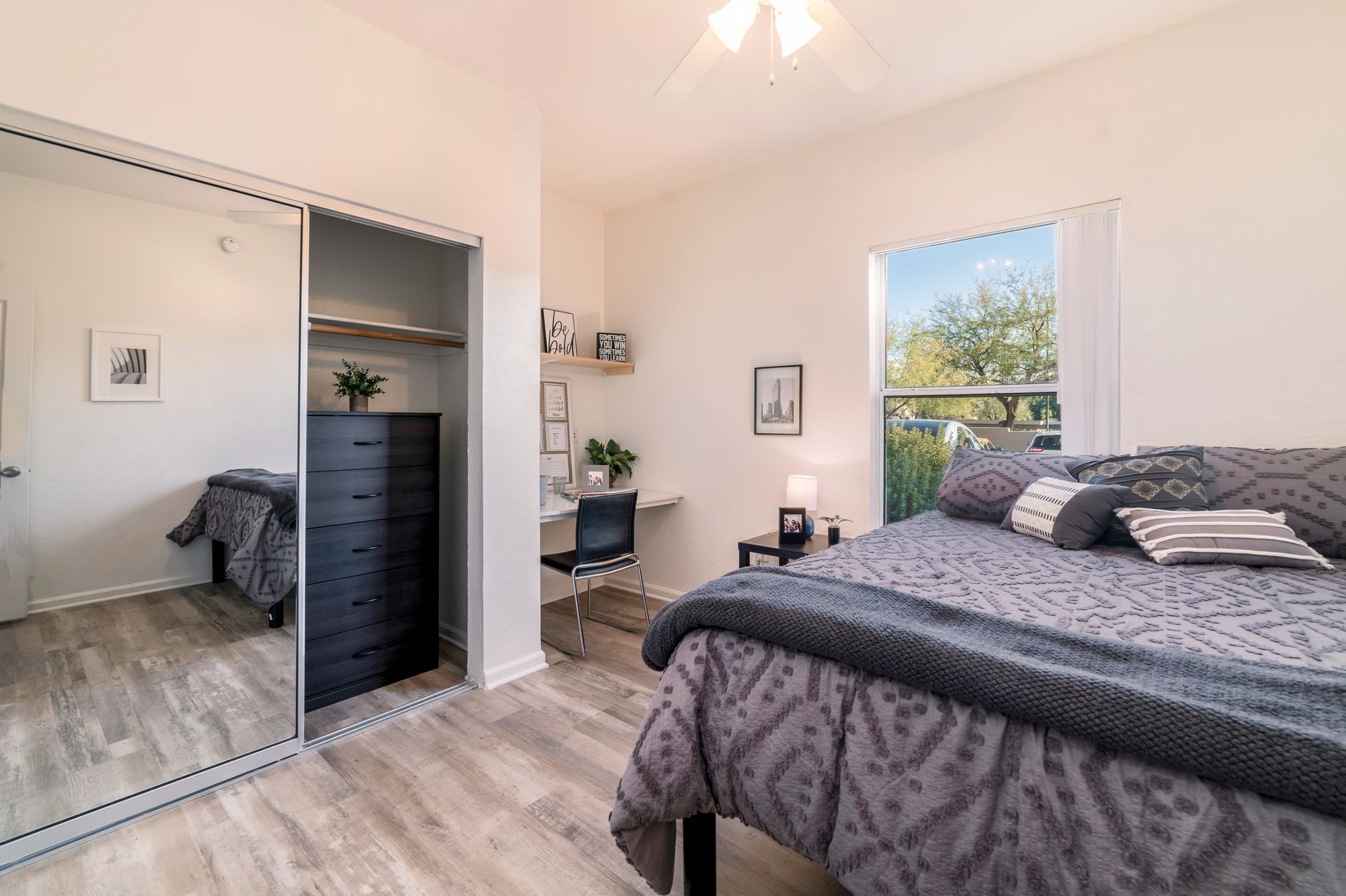 A picture of a private fully furnished bedroom at The Seasons including a bed, study nook, and closet.
