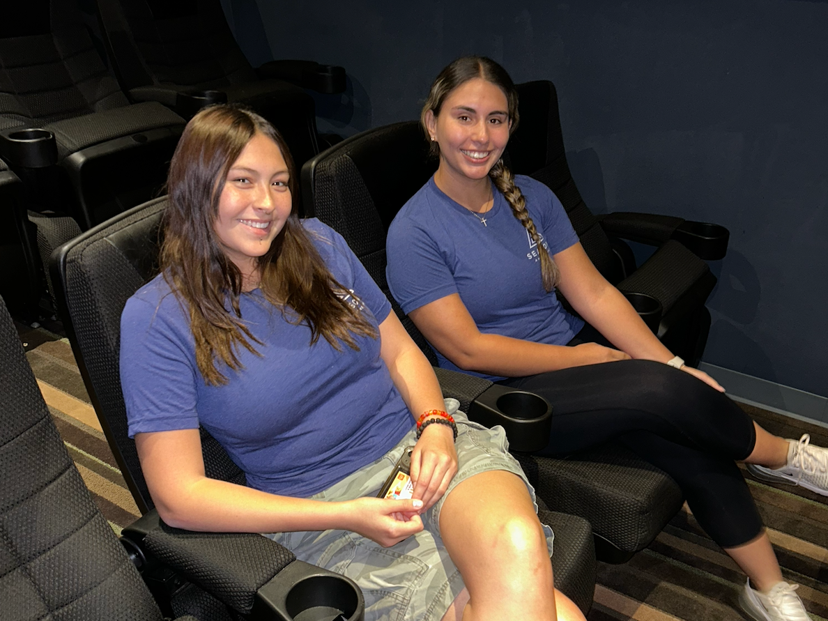 Two residents in blue logo shirts enjoy the private on-site theater.