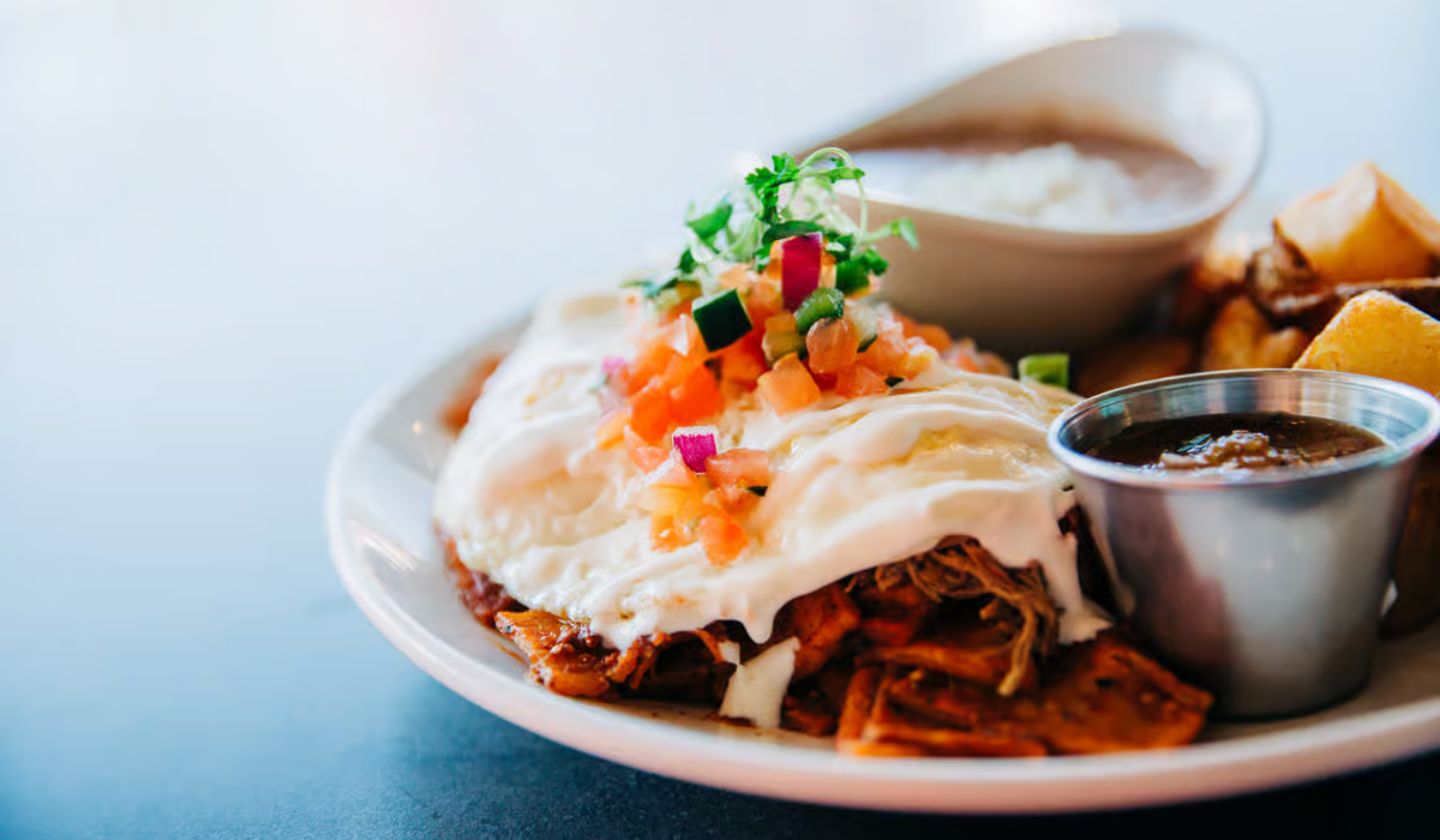 Breakfast plate at Seis Kitchen of chilaquiles, corn tortilla chips, house made chile sauce, pico de gallo and 2 fried eggs.