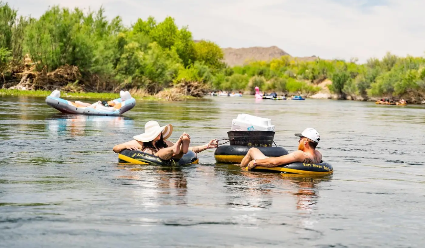 People float on tubes with sun hats and coolers on the Salt River.