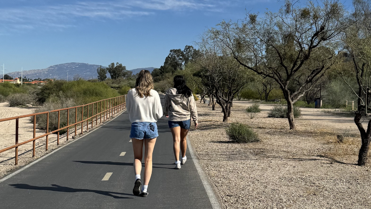 2 girls walking down paved walking path