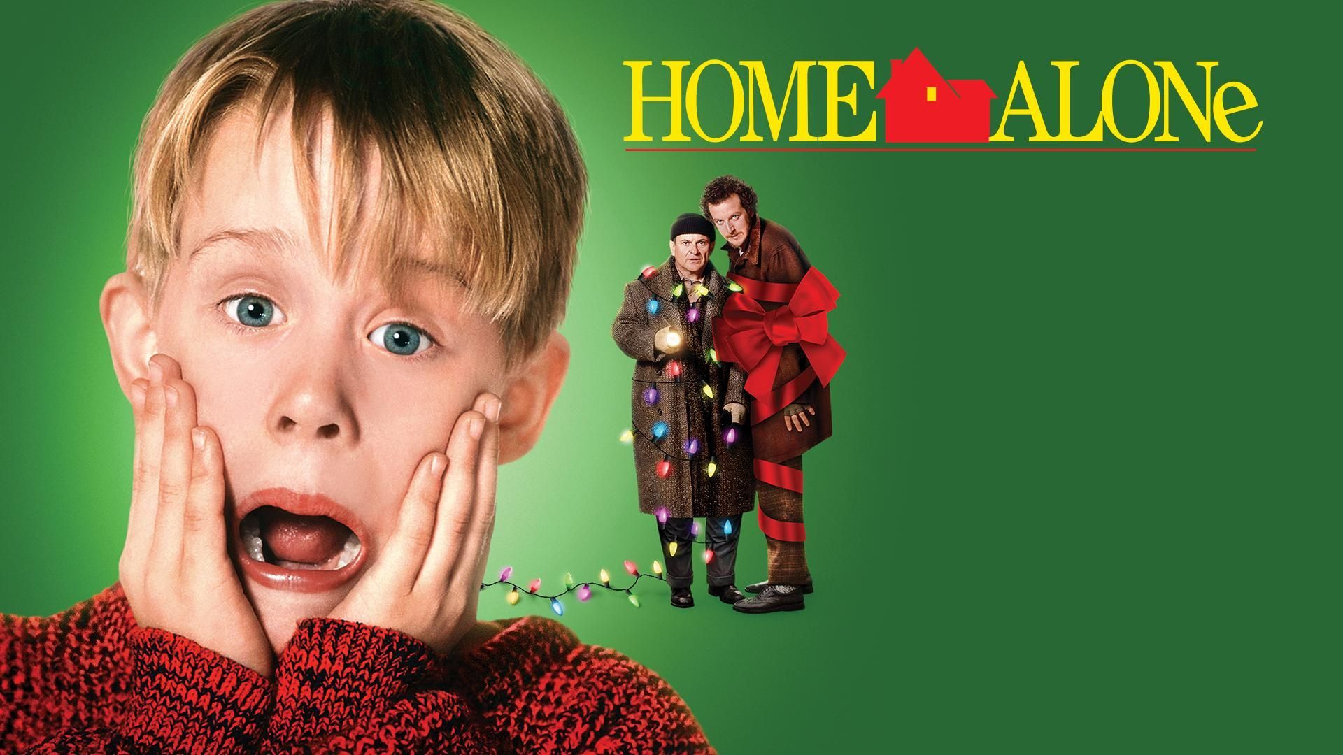 Macaulay Culkin, wide-eyed and gasping, stands in front of two criminals tangled in Christmas lights and ribbon.
