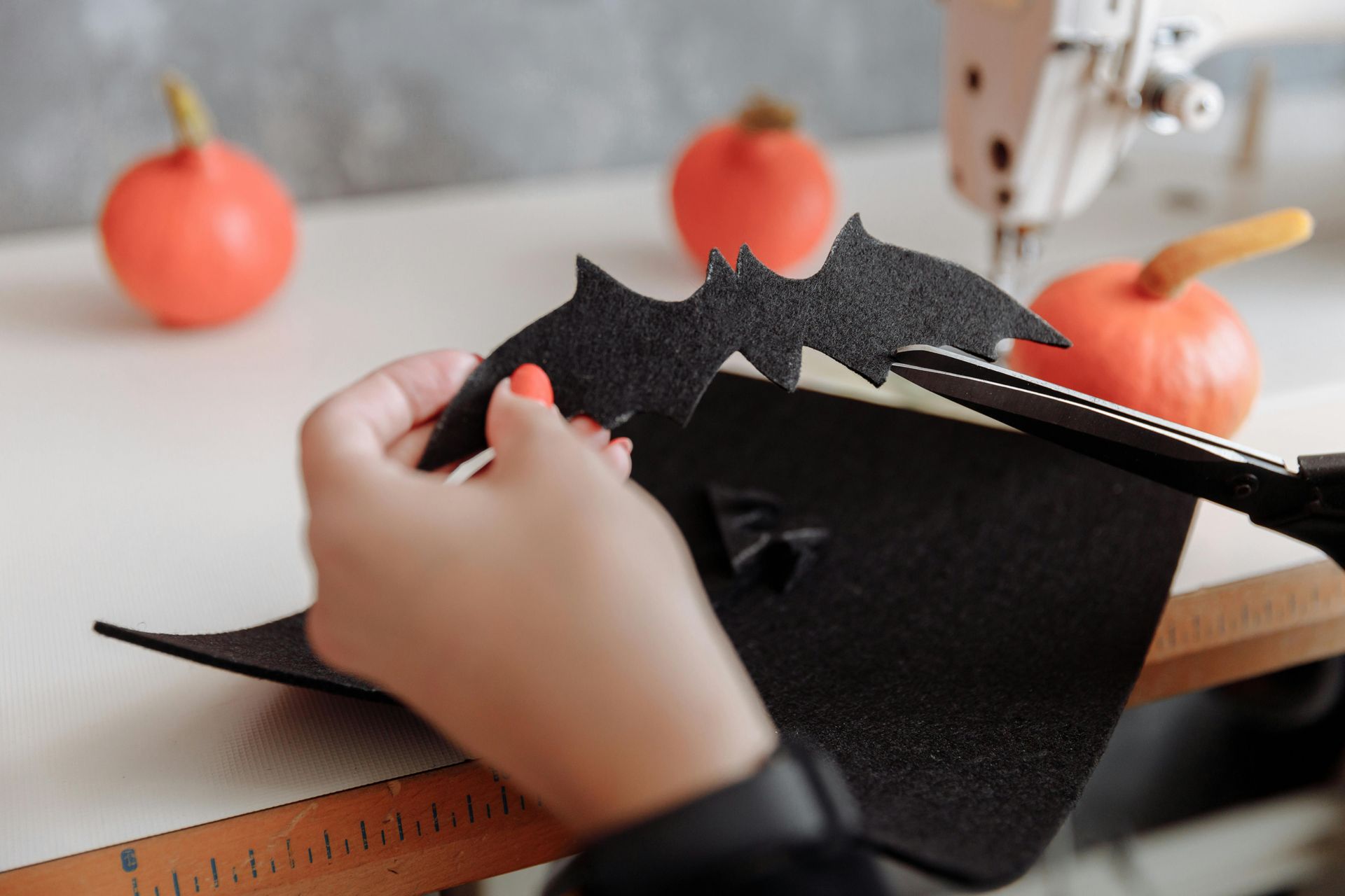 Reuse old wrapping paper, magazines, or fabric for your bats! An image of a hand holding a cut out bat and a pair of scissors.