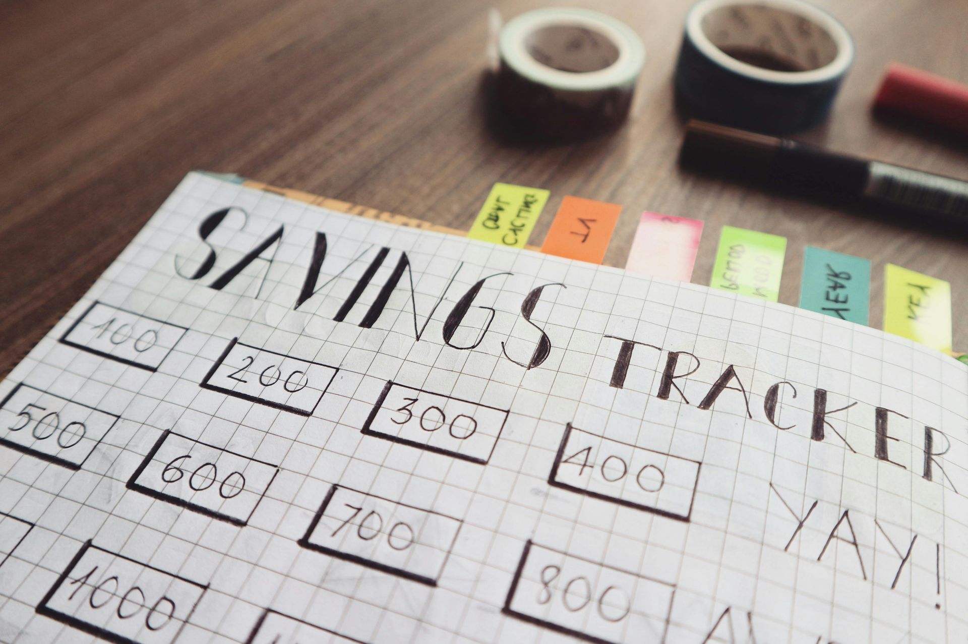 Outline your monthly expenses and set a goal! A hand drawn money savings tracker in a notebook.