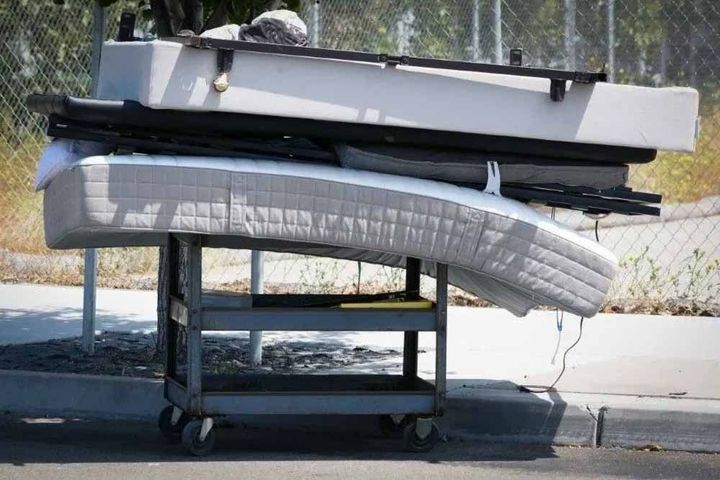 Stacked old mattresses on a metal rack for recycling, and junk removal