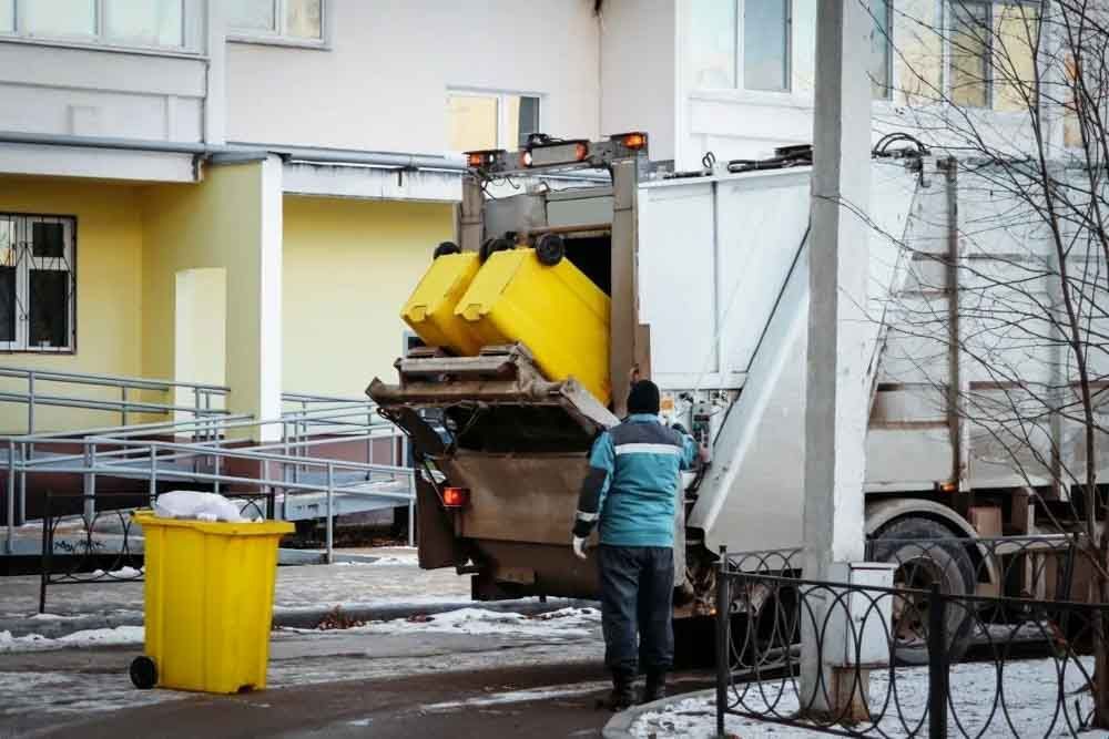 Large white garbage truck collecting waste from an office building in St. John's Newfoundland.