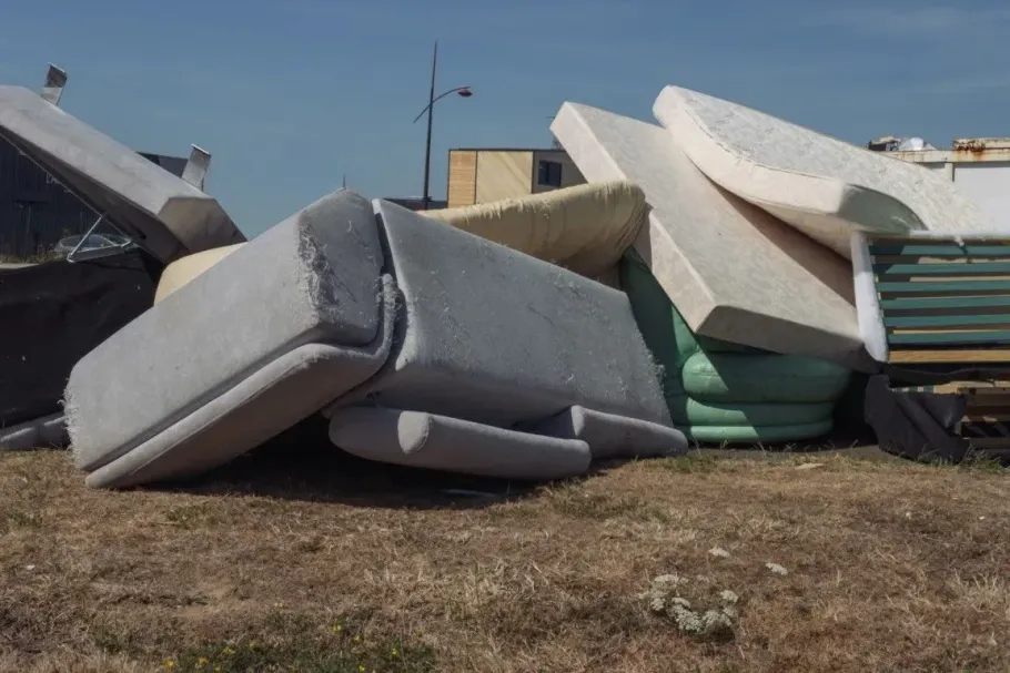 Large pile of discarded mattresses and old sofa cushions.