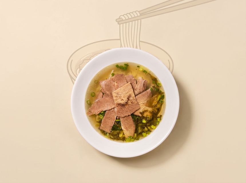 Bowl of soup with dumplings on a beige table, viewed from above