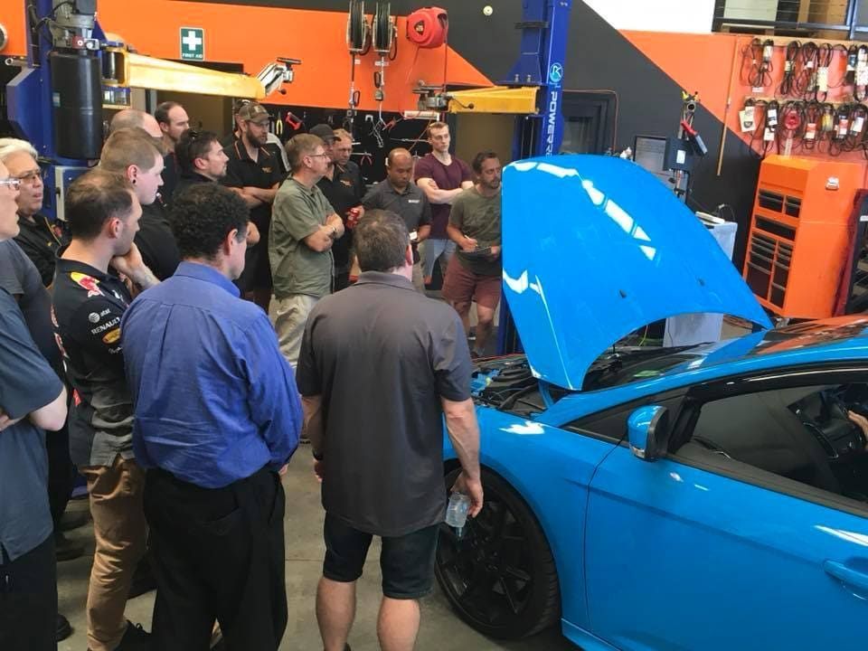 A Group Of Men Are Standing Around A Blue Car With The Hood Open — Queanbeyan Diesel Service In Queanbeyan, East NSW