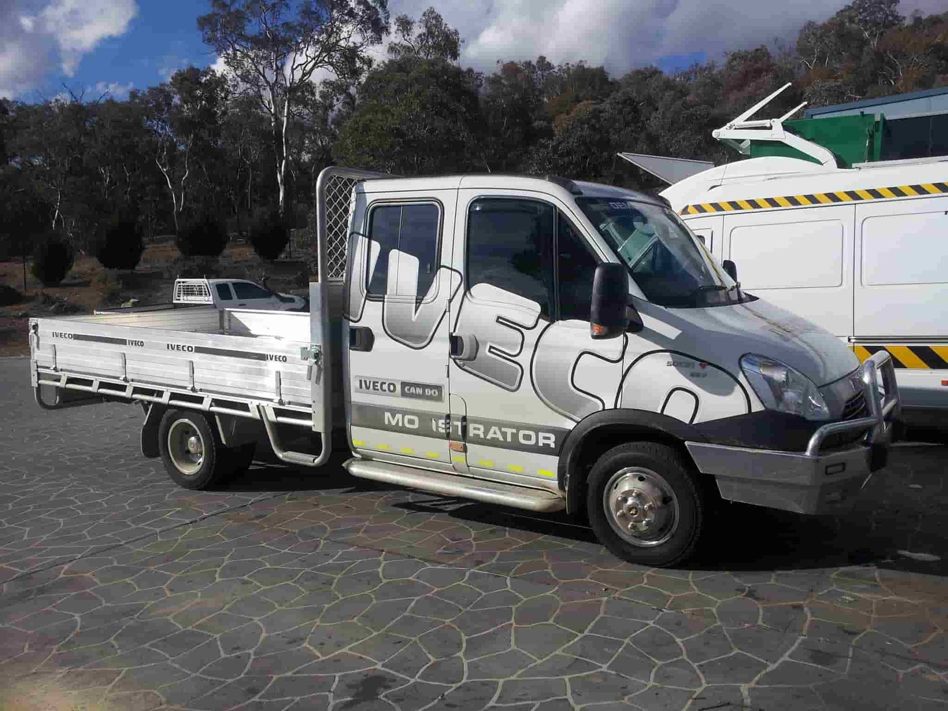 A White Truck With A Flat Bed Is Parked In A Parking Lot — Queanbeyan Diesel Service In Queanbeyan, East NSW