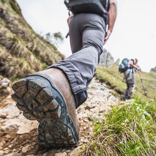A person wearing hiking boots is walking down a rocky path. A person wearing hiking boots is walking down a rocky path.