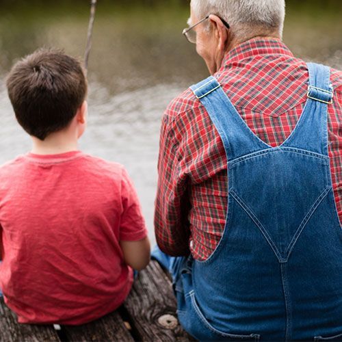 A man and a boy are sitting on a dock looking at the water. A man and a boy are sitting on a dock looking at the water.