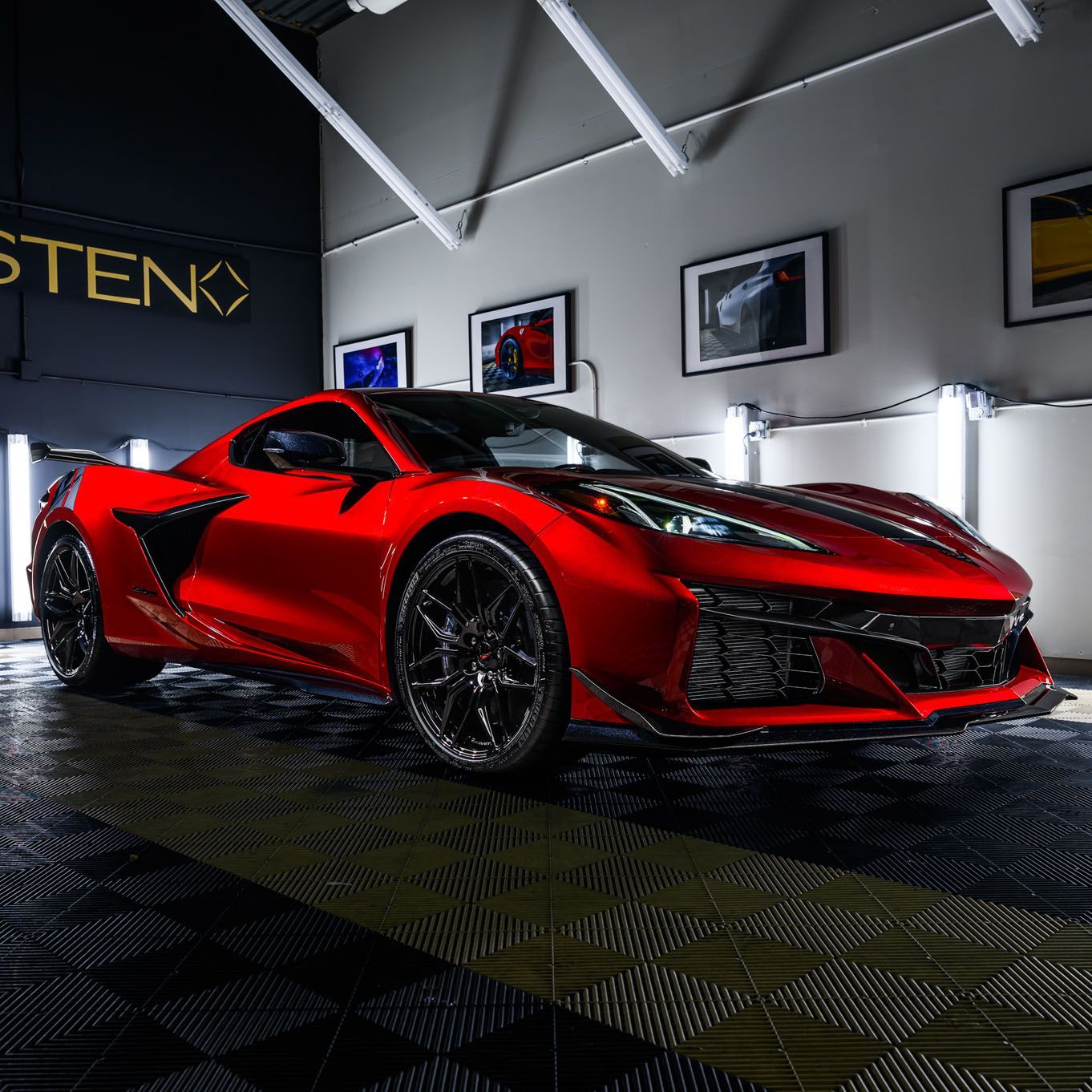 Red sports car in a garage, black wheels, glossy paint.