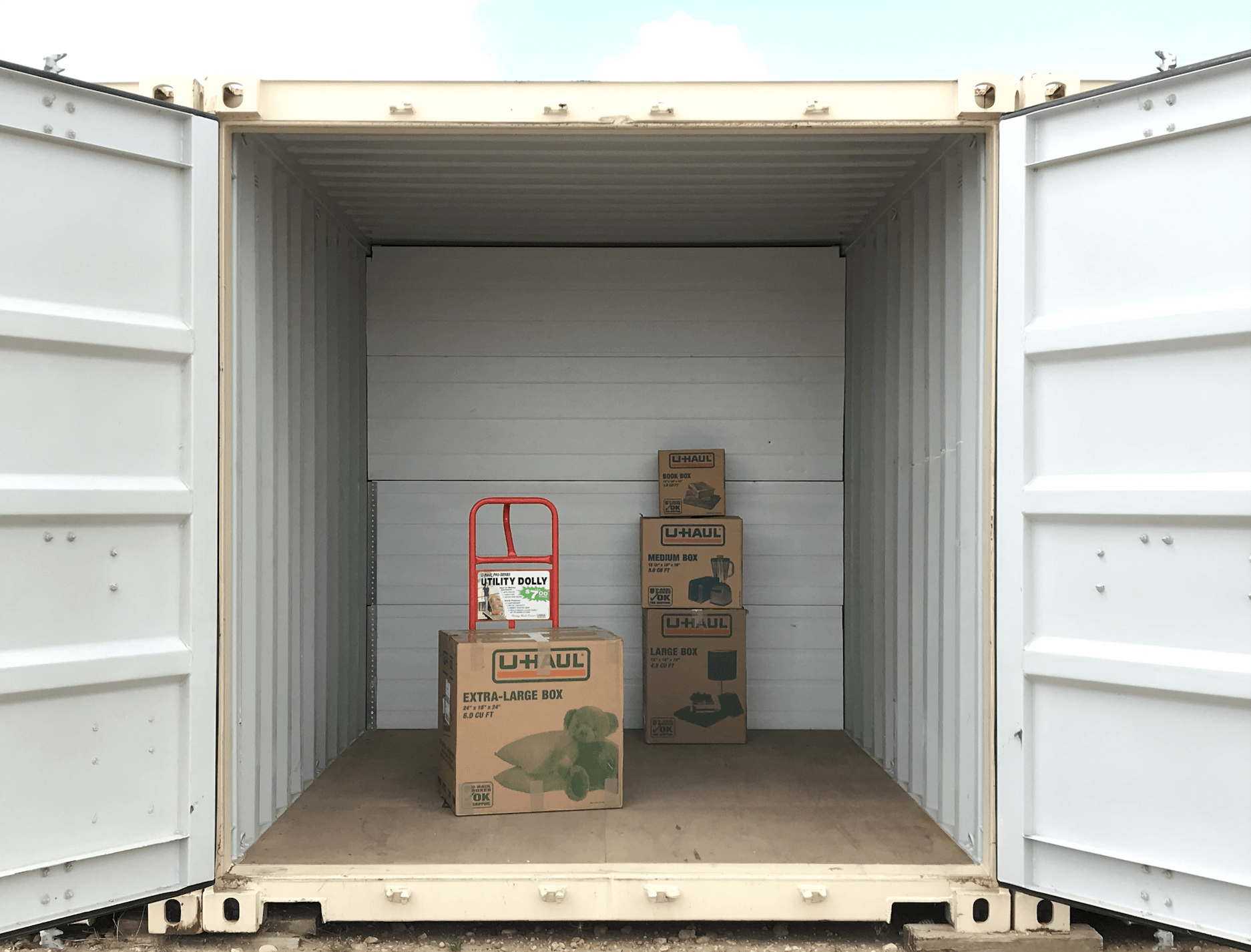 Open shipping container with stacked cardboard boxes and a hand truck inside