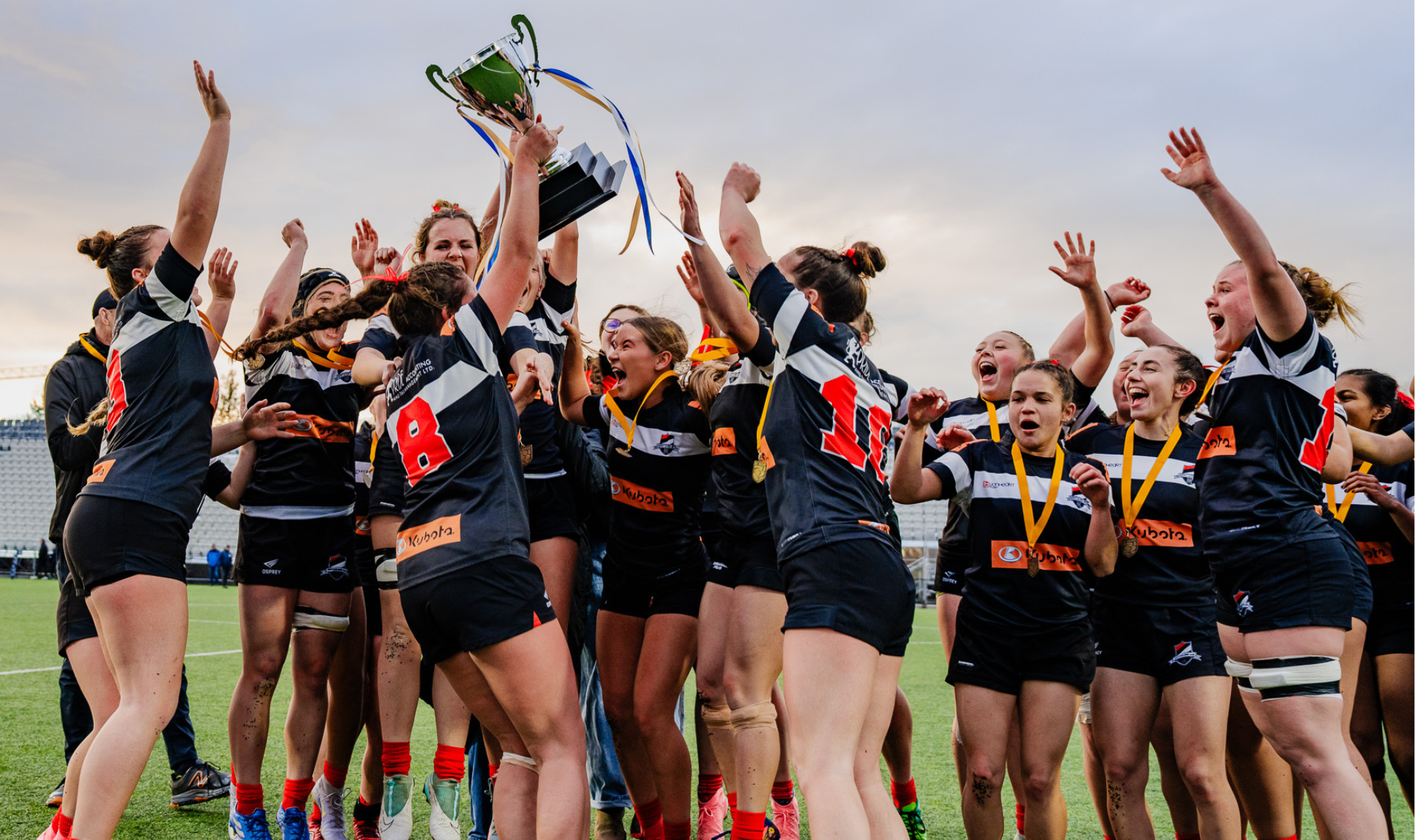 Rugby players in colorful jerseys huddle together on a field before a game