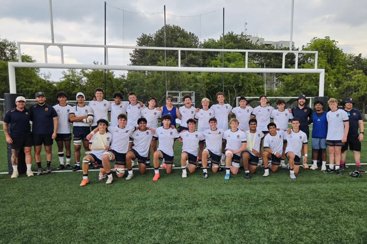 Youth soccer team posing for a group photo on a field with goals in the background