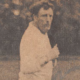 Sepia-toned man in a white shirt standing outdoors, looking toward the camera