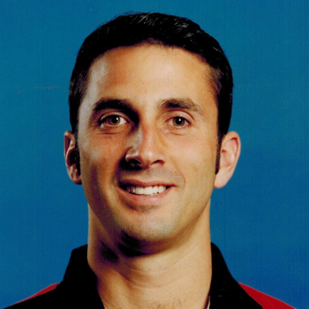 Smiling man in a black shirt against a blue background