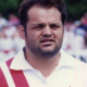 Close-up of a serious man in a red-and-white striped shirt at a sports event