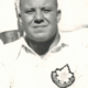 Black-and-white portrait of a man in a light shirt with a badge emblem on the chest