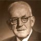 Sepia portrait of an older man with glasses and a mustache, looking slightly to the side