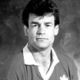 Black-and-white portrait of a man in a collared shirt and sweater, facing forward against a plain background