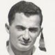 Black-and-white portrait of a smiling man with short dark hair, facing the camera.