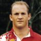 Close-up portrait of a man in a red-and-white sports jersey against a dark background