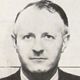Black-and-white portrait of a man in a suit, facing forward against a plain background