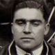 Black-and-white close-up portrait of a man with a serious expression, looking at the camera.