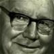 Close-up of a smiling man wearing glasses in a green-tinted portrait