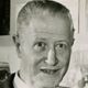 Black-and-white headshot of a smiling man with short hair and a goatee.