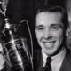 Smiling man in a suit beside a trophy or award, black-and-white portrait
