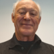 Smiling man in a black shirt against a plain beige background