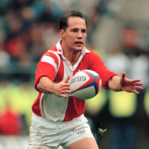 Rugby player in red and white jersey catching a ball on the field